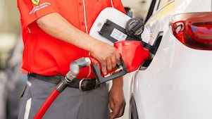 Empleado de una estacion de servicio Shell llenando tanque de gasolina en un coche blanco