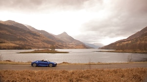 Auto azul circulando junto a un lago