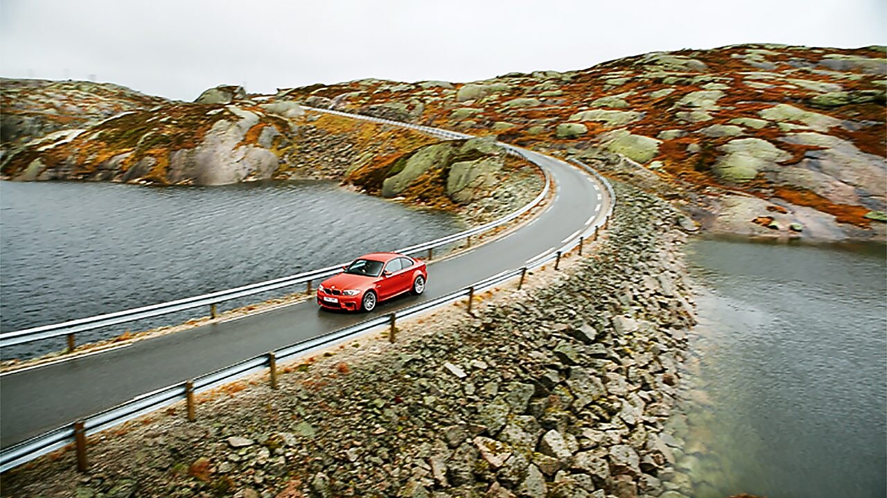Auto rojo en una carretera junto al río