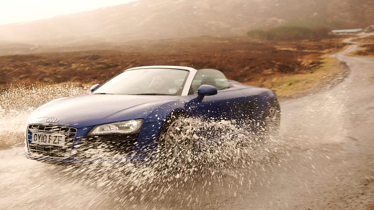 Hombre conduciendo un auto a través de un gran charco de agua