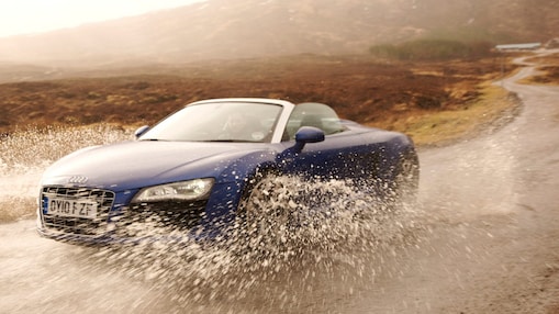 Hombre conduciendo un auto a través de un gran charco de agua
