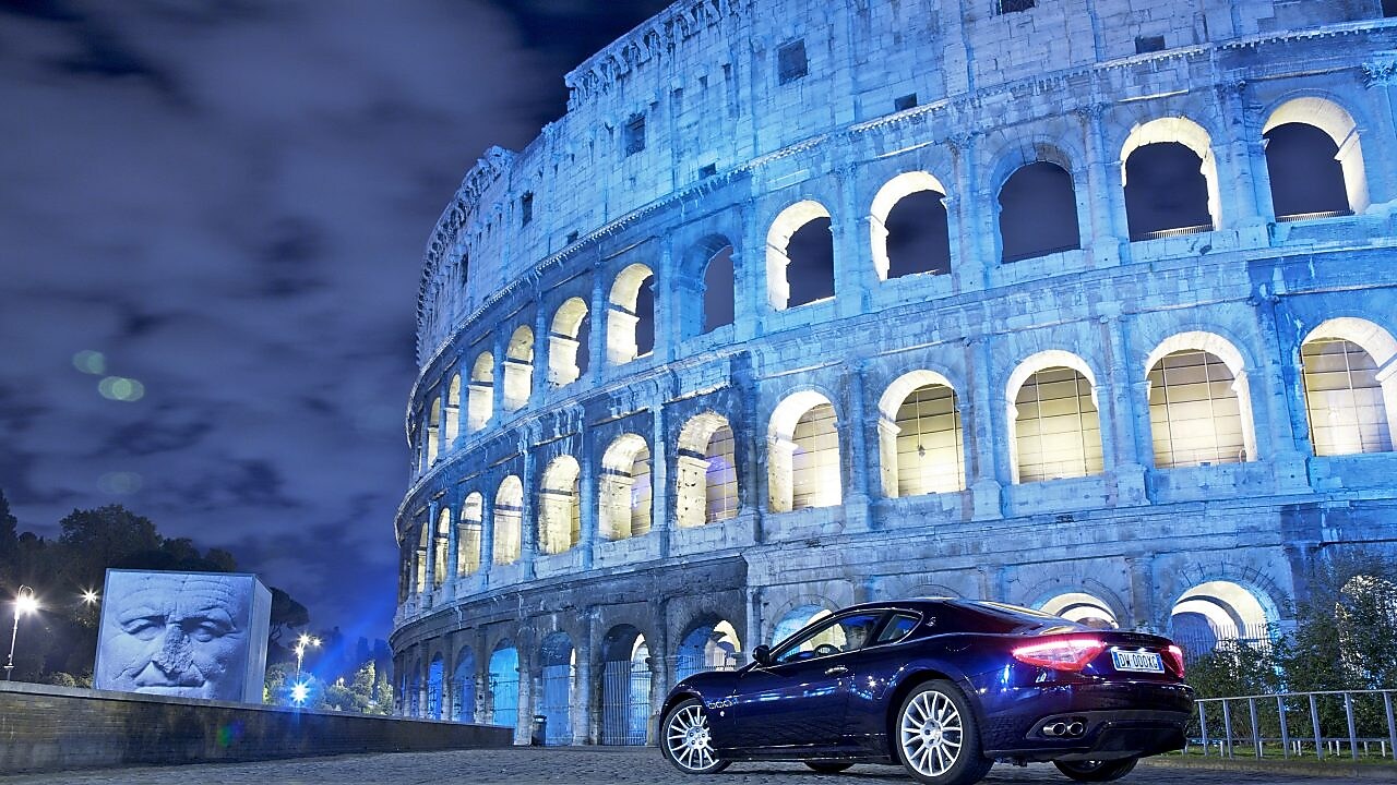 Auto estacionado en el exterior del Coliseo de Roma de noche