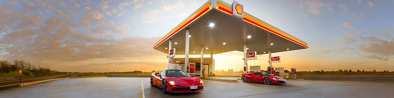 coche rojo de Ferrari en estación de servicio de Shell. Al fondo, un cielo en fin de tarde.